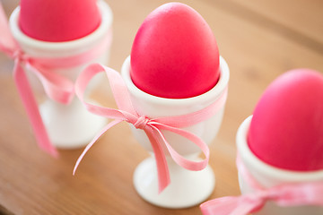 Image showing pink colored easter eggs in holders on table