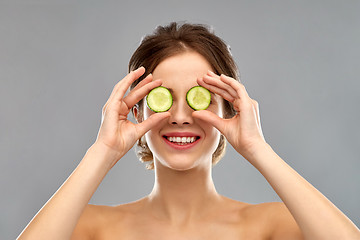 Image showing smiling woman with cucumber over grey background