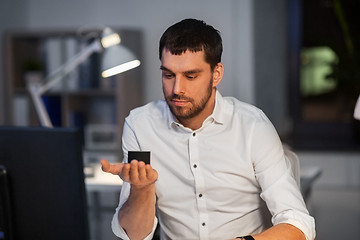 Image showing businessman using smart speaker at night office