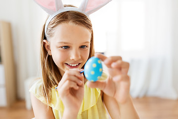 Image showing happy girl coloring easter eggs at home