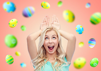 Image showing happy smiling young woman making easter bunny ears