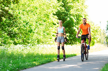 Image showing happy couple with rollerblades and bicycle riding