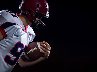 Image showing American football player holding ball while running on field