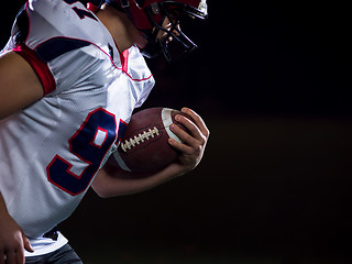 Image showing American football player holding ball while running on field