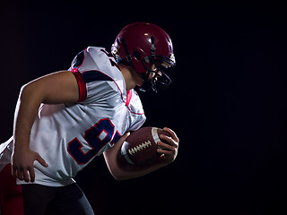 Image showing American football player holding ball while running on field