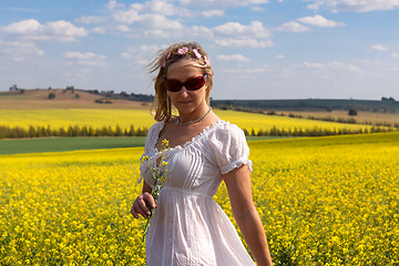 Image showing Female  by a field of flowering canola and rolling hills