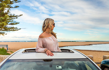 Image showing Road trip summer beach vibes.  Carefree woman in sunroof car by 