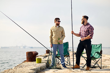 Image showing happy friends with fishing rods and beer on pier