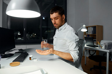 Image showing businessman taking medicine pill at night office