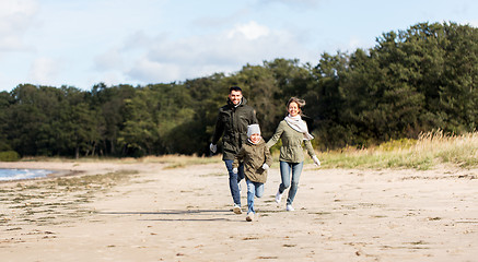 Image showing happy family running along autumn beach