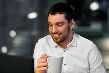 Image showing businessman drinking coffee at night office