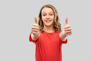 Image showing smiling teenage girl in red showing thumbs up