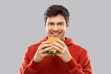 Image showing happy young man eating hamburger