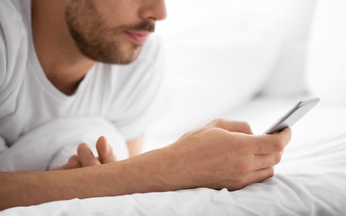 Image showing close up of man with smartphone in bed in morning