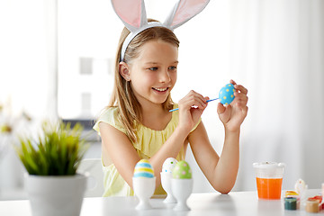 Image showing happy girl coloring easter eggs at home