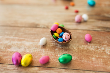 Image showing chocolate egg and candy drops on wooden table