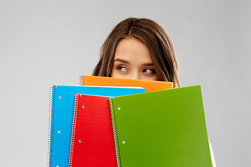 Image showing teenage student girl hiding behind notebooks