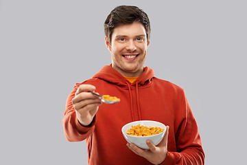 Image showing smiling young man in red hoodie eating cereals