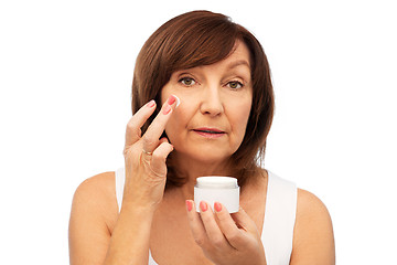 Image showing senior woman applying cream to her face