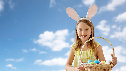 Image showing happy girl with colored easter eggs over blue sky