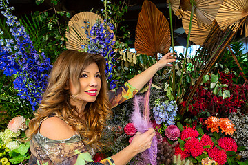 Image showing Woman standing outside a florist choosing flowers