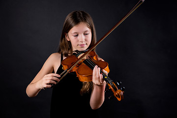 Image showing Young professional violinist playing and exercising on black background