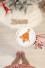 Image showing Female holding cappuccino with Christmas tree design on froth