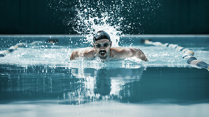 Image showing dynamic and fit swimmer in cap breathing performing the butterfly stroke