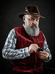 Image showing dramatic portrait of senior smoking tobacco pipe