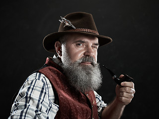 Image showing dramatic portrait of senior smoking tobacco pipe