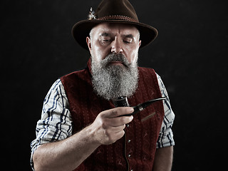 Image showing dramatic portrait of senior smoking tobacco pipe