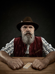 Image showing bearded man clogs the tobacco in pipe