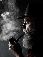 Image showing Black and white dramatic portrait of senior smoking tobacco pipe