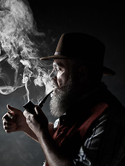 Image showing Black and white dramatic portrait of senior smoking tobacco pipe