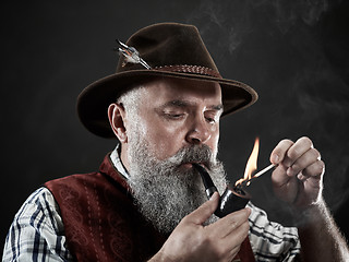 Image showing dramatic portrait of senior smoking tobacco pipe