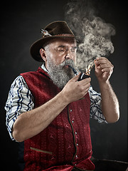 Image showing dramatic portrait of senior smoking tobacco pipe