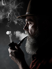 Image showing Black and white dramatic portrait of senior smoking tobacco pipe