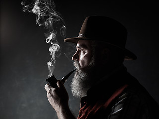 Image showing Black and white dramatic portrait of senior smoking tobacco pipe