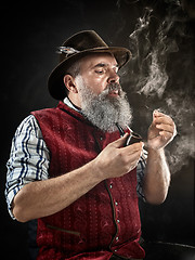 Image showing dramatic portrait of senior smoking tobacco pipe