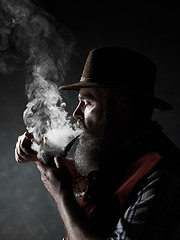 Image showing Black and white dramatic portrait of senior smoking tobacco pipe