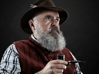 Image showing dramatic portrait of senior smoking tobacco pipe