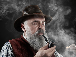 Image showing dramatic portrait of senior smoking tobacco pipe