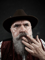 Image showing dramatic portrait of senior smoking tobacco pipe