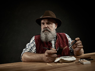 Image showing bearded man clogs the tobacco in pipe