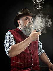 Image showing dramatic portrait of senior smoking tobacco pipe