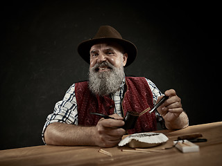 Image showing bearded man clogs the tobacco in pipe