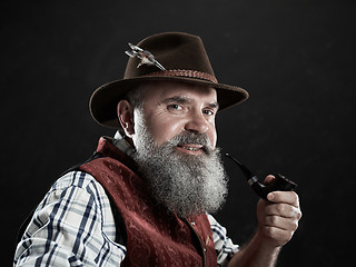 Image showing dramatic portrait of senior smoking tobacco pipe