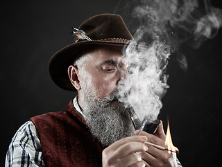 Image showing Black and white dramatic portrait of senior smoking tobacco pipe