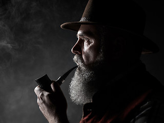 Image showing Black and white dramatic portrait of senior smoking tobacco pipe