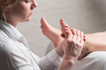 Image showing Professional female masseur giving reflexology massage to woman foot